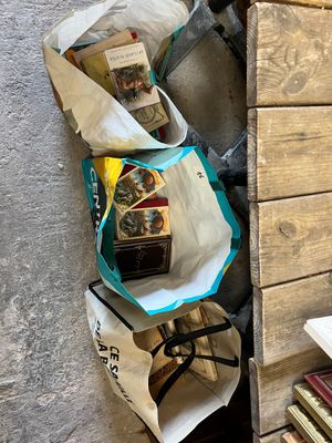 plusieurs sacs remplis de livres posés sur une étagère à côté d'une bibliothèque