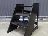 an image of a black step stool in front of a metal wall