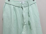green pants hanging on a hanger in front of a white wall
