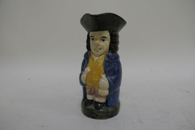 une figurine représentant un homme vêtu d'un manteau bleu et d'un chapeau