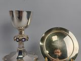 a silver chalicet and a silver plate with a picture of a woman on it