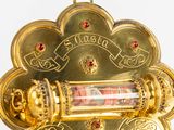 a gold plated clock with red stones on it