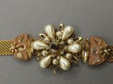 un gros plan sur un bracelet en or orné de perles et d'autres pierres précieuses