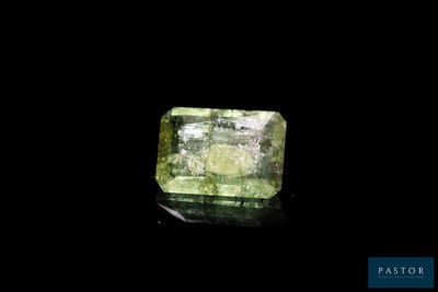 a green diamond on a black surface with a black background