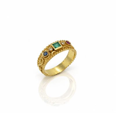 un gros plan d'une bague en or sertie d'émeraudes et de saphirs