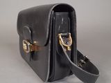 black leather handbag with gold hardware on a grey background