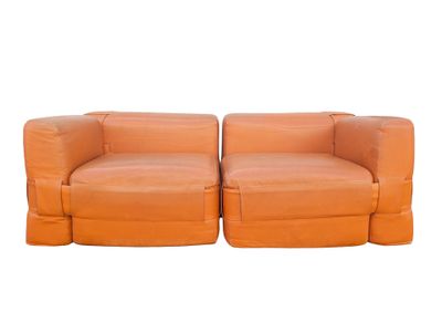 pair of orange leather sofas with ottomans on white background