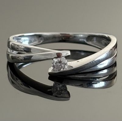 silver ring with a single diamond on top of a black surface