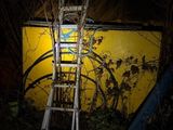 une échelle appuyée contre un mur jaune dans l'obscurité
