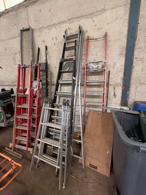 de nombreuses échelles empilées dans un garage