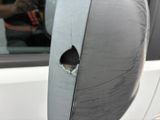 a hole in the side mirror of a white car