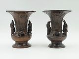 pair of bronze vases with figures on them on a white background
