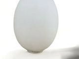 a white egg sitting on top of a table next to a knife