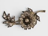 un gros plan d'une broche en forme de fleur posée sur une surface blanche