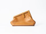 un sac à main en cuir marron posé sur une surface blanche