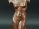 une photo d'une statue en bronze représentant une femme, posée sur un socle en bois
