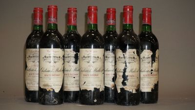 six bouteilles de vin rouge sont alignées sur une table