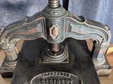 une vieille presse à imprimer en fonte posée sur une table en bois