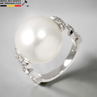 une photo d'une bague en perle blanche et diamants posée sur une table
