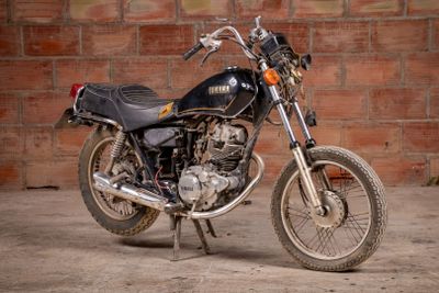 a black motorcycle parked in front of a brick wall