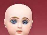a small doll with blue eyes sitting on a table