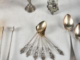 many silver spoons and silverware on a white table