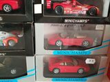 four red toy cars on display in a display case