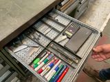 un tiroir rempli de stylos et de crayons, dans lequel se trouve une calculatrice