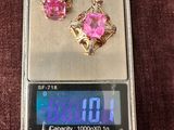 une petite balance sur laquelle sont posées une paire de boucles d'oreilles roses