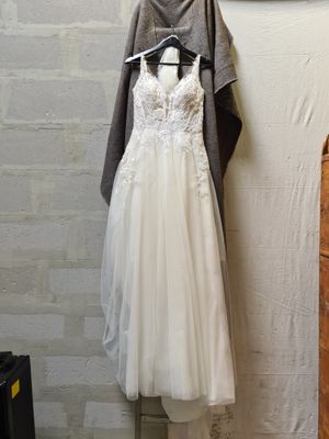 a wedding dress hanging on a hanger next to a brick wall