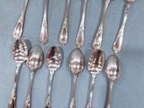 six cuillères en argent sont disposées en rangée sur un fond bleu