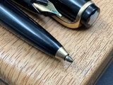 two pens sitting on top of a piece of wood