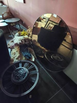 un grand miroir rond accroché au mur, à côté d'une table sur laquelle se trouve un vase de fleurs