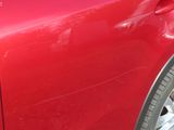 a close up of a red car with a broken door handle