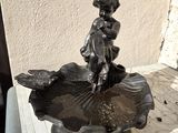 a small statue of a girl sitting on a fountain