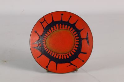 an orange plate with black designs on it on a white surface