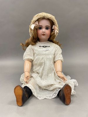 une image représentant une poupée assise par terre, vêtue d'une robe et d'un chapeau