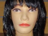 une tête de mannequin coiffée d'une perruque noire