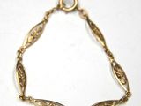 a close up of a gold bracelet on a white surface