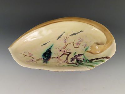 un petit objet en forme de coquillage orné d'oiseaux et de fleurs