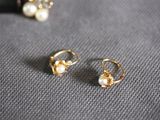 a pair of pearl and gold earrings on a gray surface
