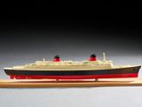 une petite maquette de bateau posée sur un socle en bois