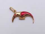 a gold and red bird charm on a white surface