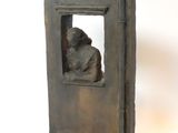 une petite statue représentant un homme assis près d'une fenêtre