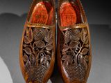 pair of wooden shoes with carved design on them on a table