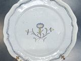 une assiette blanche ornée d'une fleur bleue et jaune