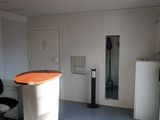 a room with a desk, chair, and refrigerator in it