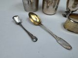 a lot of silver spoons and silver cups on the table