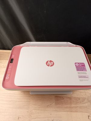 L'imprimante HP est posée sur la table, devant un mur noir.