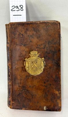 an old book with a gold emblem on it sitting on a white surface